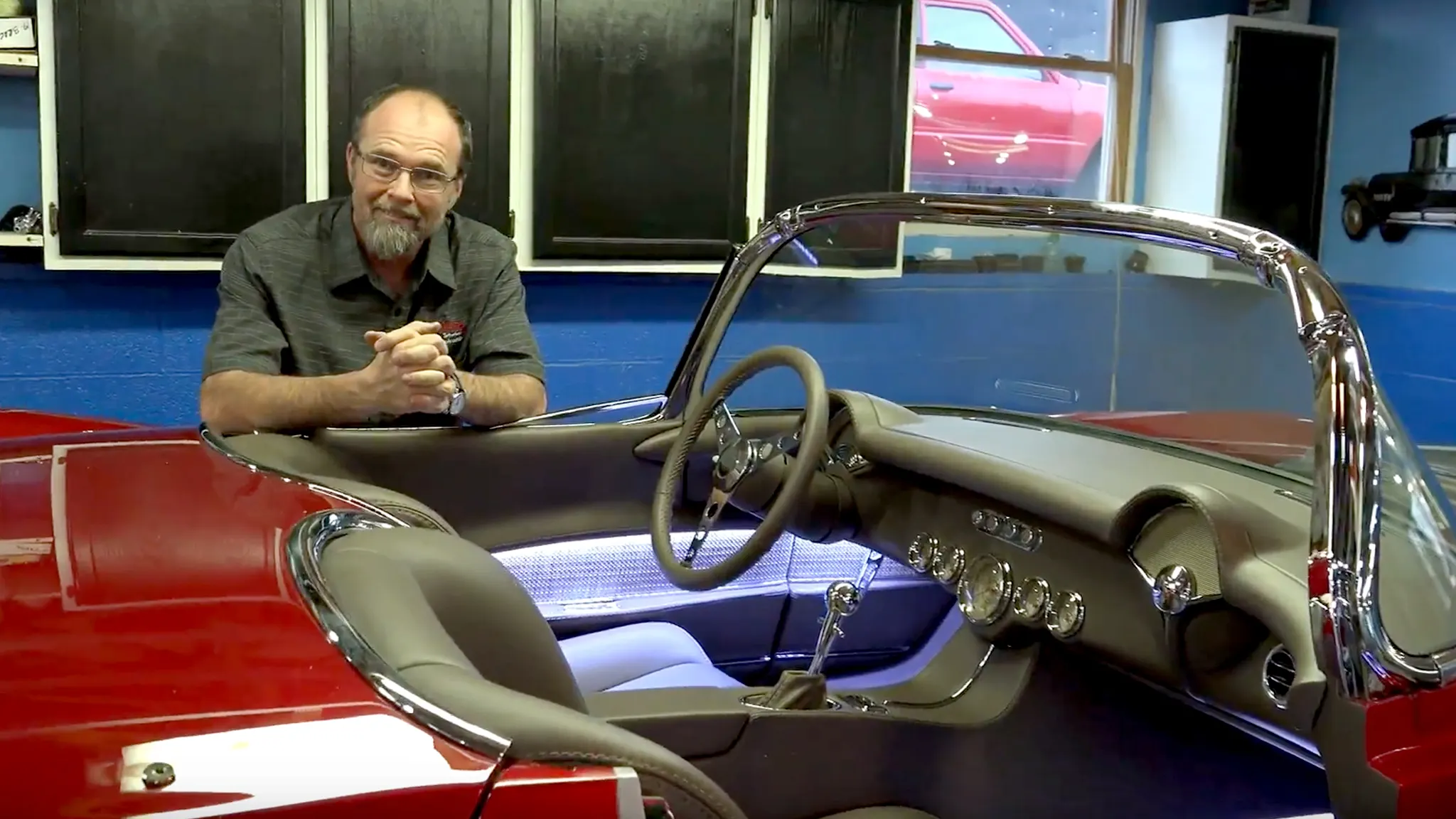 Steve Holcomb leaning on a red Corvette with a gray custom interior
